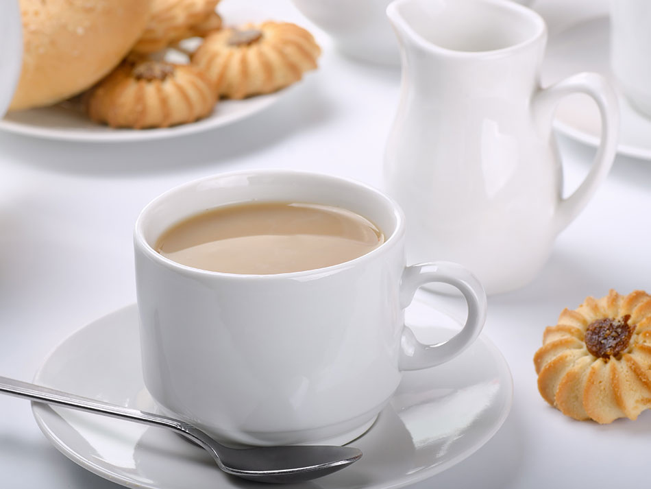 Чай с молоком в чашке на блюдце и молочник