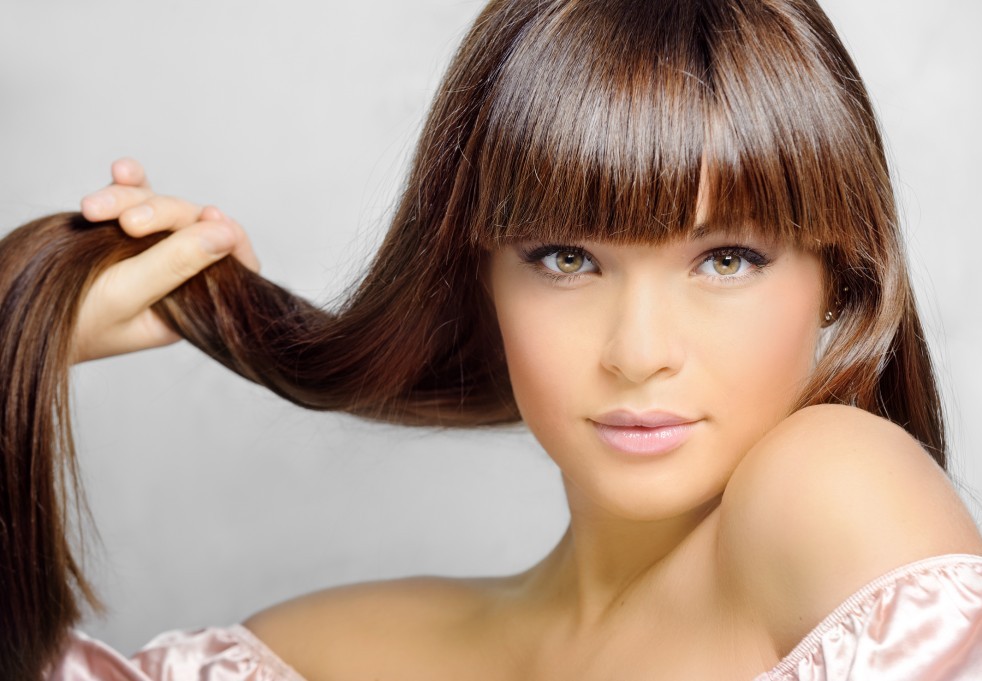 Девушка держит прядь своих волос, показывая их красоту