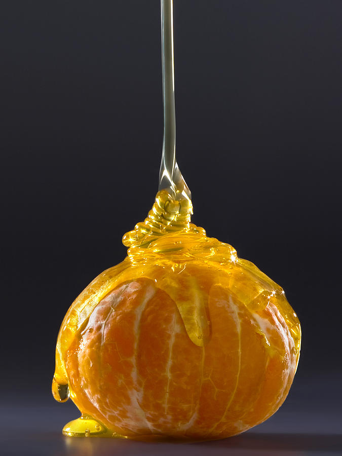 Мандарин без кожуры, сверху на него течёт прозрачный мёд