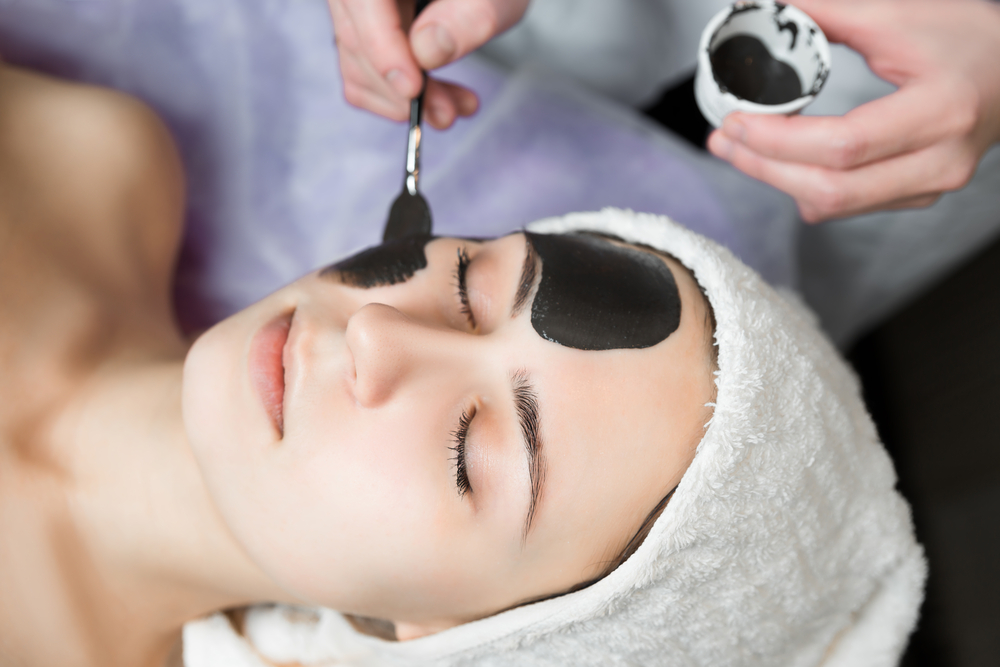 Девушке наносят маску на проблемные участки кожи лица