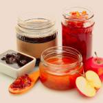 Разные виды варенья, деревянная ложка и яблоки