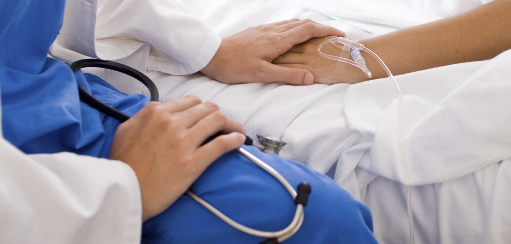 Руки врача со стетоскопом и больного — с капельницей
