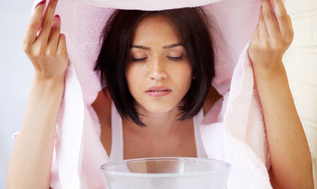 Девушка наклоняет лицо над ёмкостью с отваром