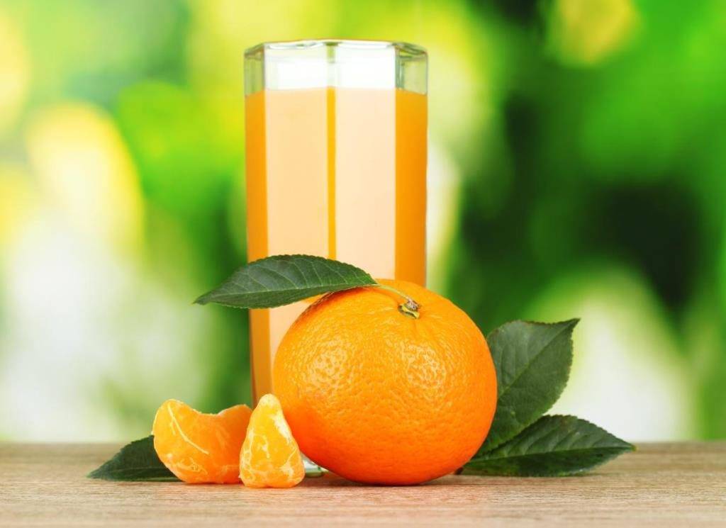 Стакан мандаринового сока, мандарин с листиками, дольки