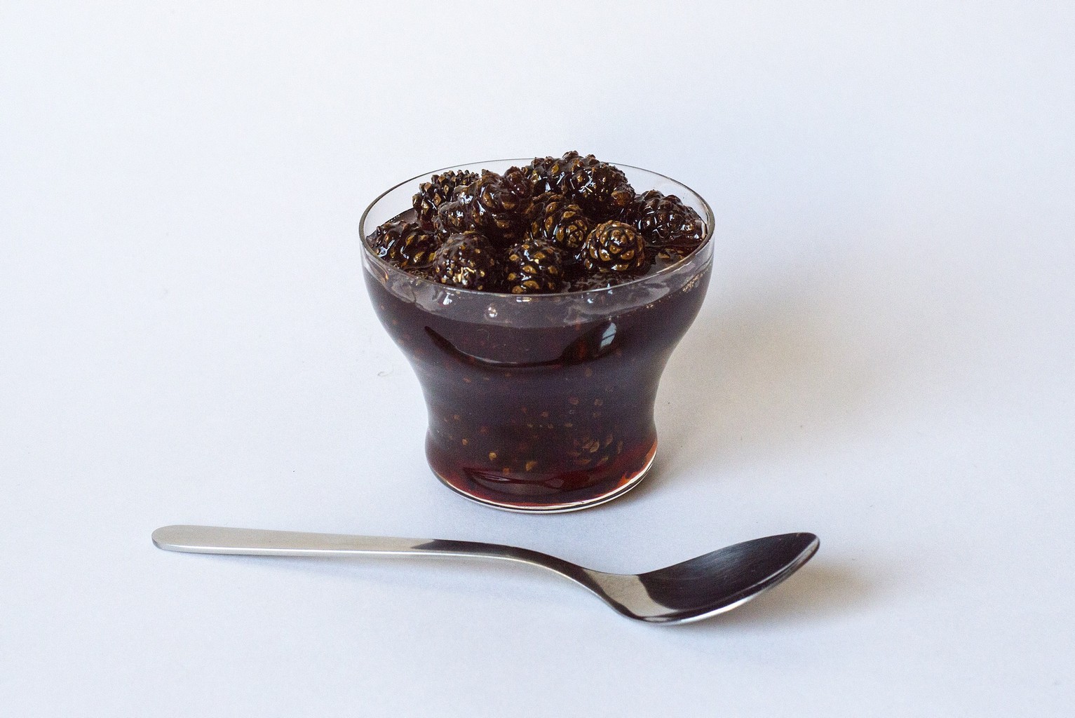Варенье из шишек в стакане с ложечкой