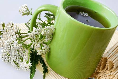 Зелёная чашка с чаем и цветы тысячелистника